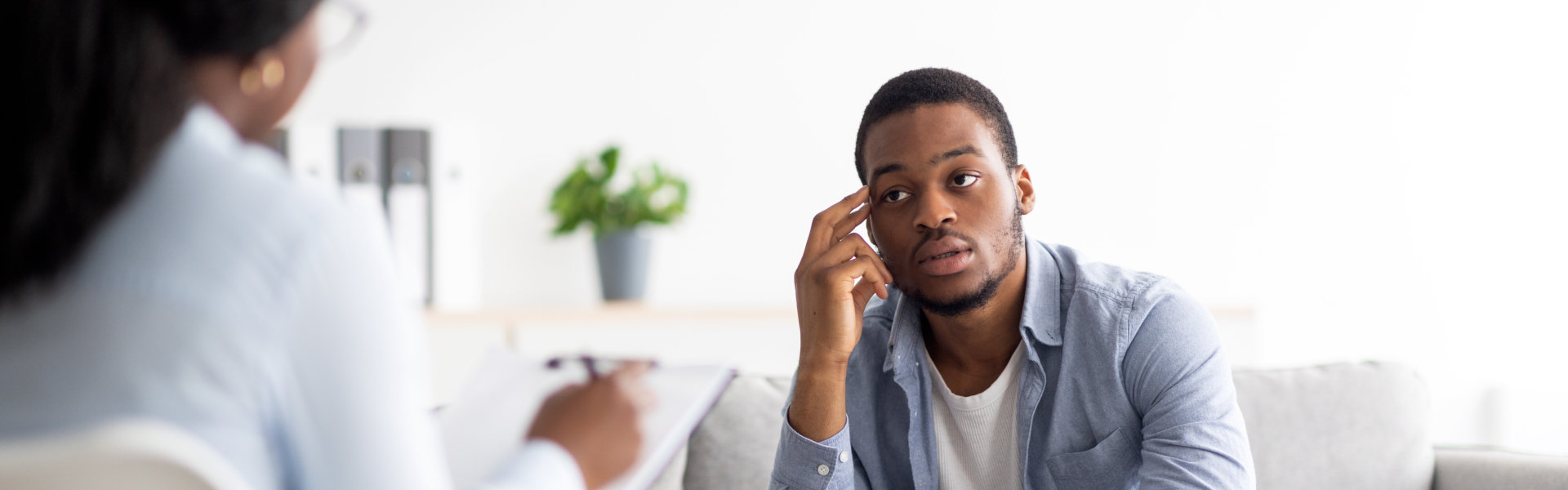 man pointing at his head and talking to his therapist